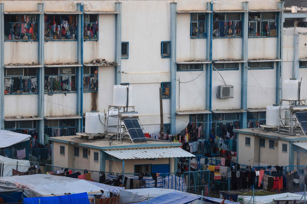 A picture shows hanging laundry belonging to internally displaced Palestinians who have fled the northern Gaza Strip due to intense Israeli military bombardment, in the grounds of a public school where they shelter in Khan Yunis in the southern Gaza Strip on November 16, 2023. Photo by MAHMUD HAMS / AFP