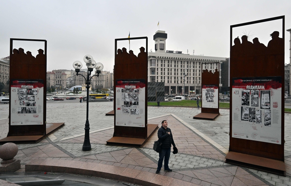 A man mourns at an open air memorial exhibition devoted to Maidan Revolution on Independence Square in Kyiv on November 17, 2023. (Photo by Sergei Supinsky / AFP)
 