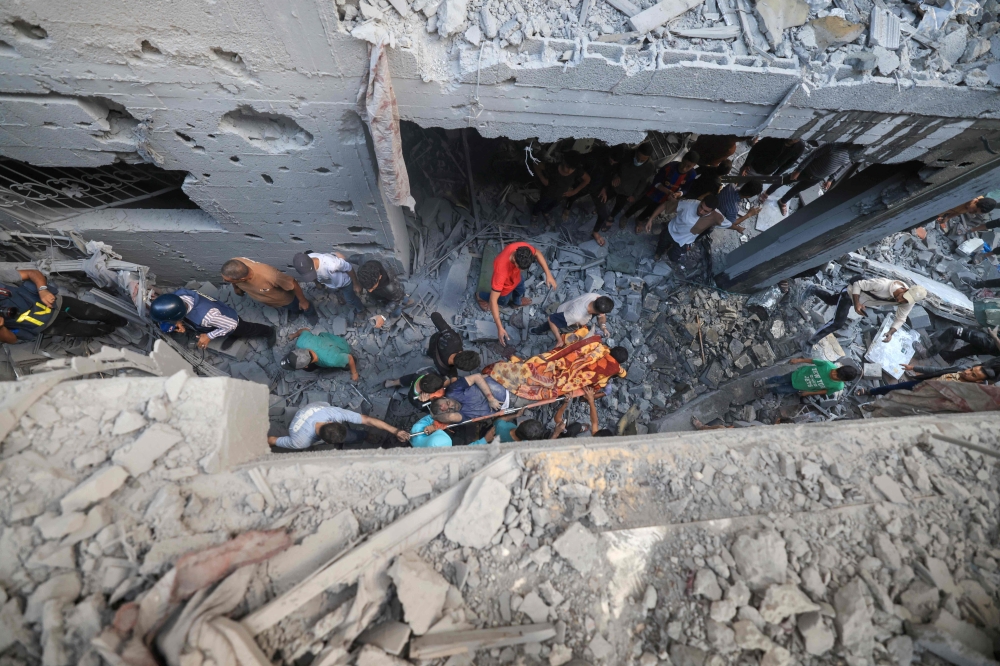 Palestinians carry an injured person pulled from the rubble following Israeli bombardment in Khan Yunis in the southern Gaza Strip on November 18, 2023 amid ongoing battles between Israel and the Palestinian militant group Hamas. (Photo by MAHMUD HAMS / AFP)

