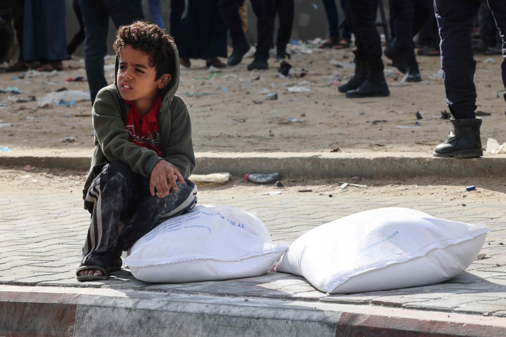 Palestinians receive bags of flour at the United Nations Relief and Works Agency for Palestine Refugees (UNRWA) distribution center in the Rafah refugee camp in the southern Gaza Strip on November 21, 2023. Photo by SAID KHATIB / AFP