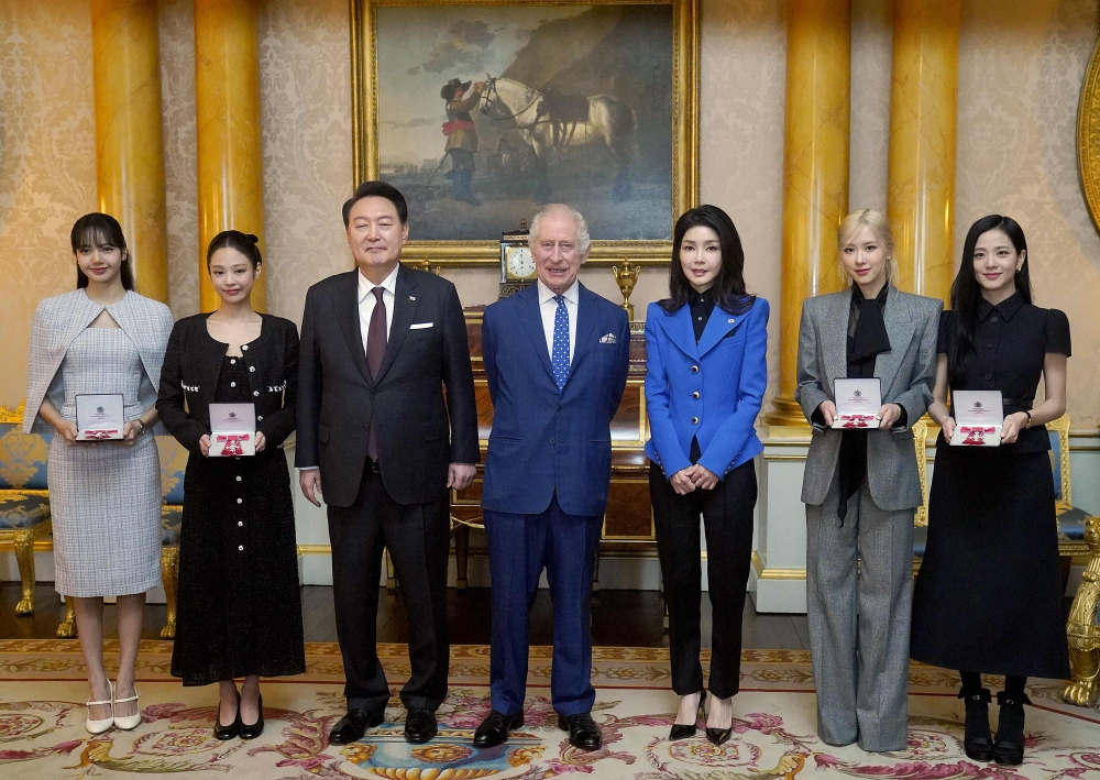 Britain's King Charles III (C) stands with South Korea's President Yoon Suk Yeol (3L), South Korea's First Lady Kim Keon Hee (3R), and K-Pop band Blackpink's members, from left, Lalisa Manoban, Jennie Kim, Roseanne Park and Jisoo Kim following a special investiture ceremony to present the band's members with Honorary MBEs (Member of the Order of the British Empire), at Buckingham Palace in London on November 22, 2023, on the second day of the President's three-day state visit to the UK. (Photo by Victoria Jones / POOL / AFP)
