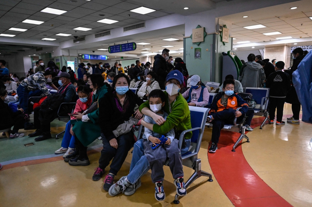 Children and their parents wait at an outpatient area at a children hospital in Beijing on November 23, 2023. (Photo by Jade Gao / AFP)
