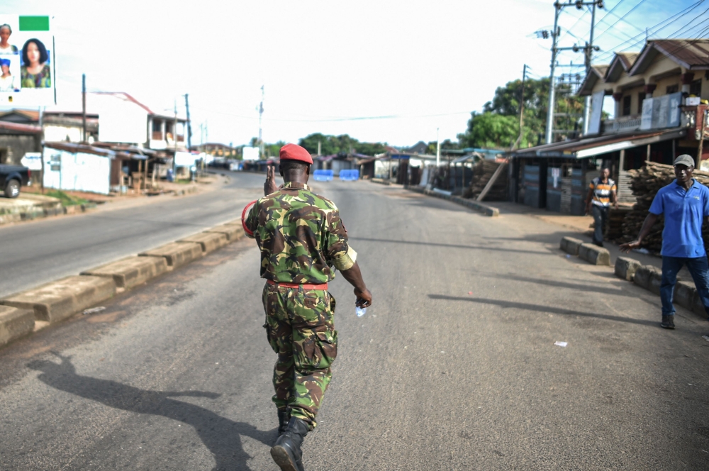 A soldier with the Sierra Leonean military police greets a man along an empty road in Freetown on November 26, 2023. (Photo by Saidu Bah / AFP)
 