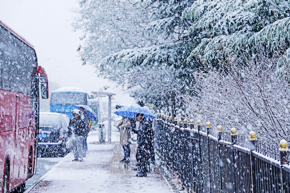 Commuters wait for transport at a bus station during snowfall in Dalian, in China's northeastern Liaoning province on November 23, 2023. Photo by AFP