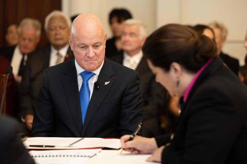 New Zealand's new PM Christopher Luxon (L) looks on as New Zealand's Governor General Dame Cindy Kiro signs documents during the swearing-in of the new government at Government House in Wellington on November 27, 2023. (Photo by Marty Melville / AFP)