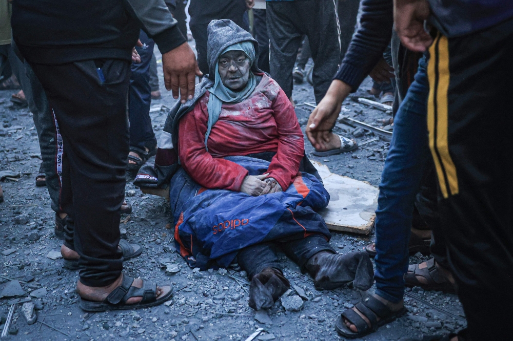 A woman injured in an Israeli strike sits amid the rubble in Rafah in the southern Gaza Strip on December 3, 2023. (Photo by Said Khatib / AFP)
