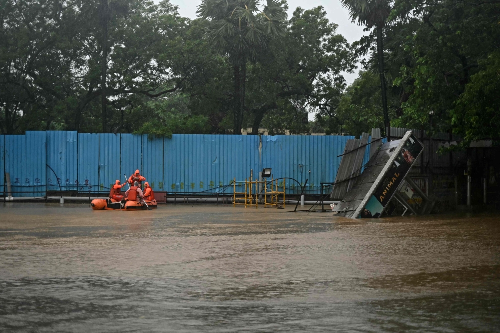 National Disaster Response Force (NDRF) personnel row a boat through a flooded street in Chennai on December 4, 2023.  (Photo by R Satish Babu/ AFP)
