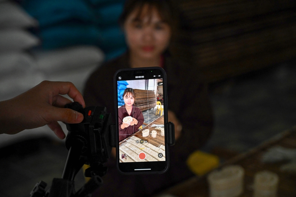 This photo taken on November 7, 2023 shows a mobile phone being used to shoot a TikTok video of TikToker Vi Thi Anh sorting out noodles at her workshop in Bac Giang province. Photo by Nhac NGUYEN / AFP