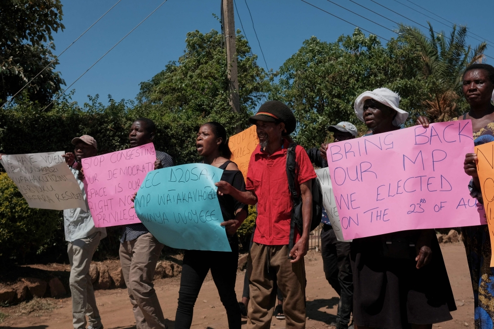 Party supporters hold placards as they protest outside the home of recalled Member of Parliament for Mabvuku-Tafara constituency, Munyaradzi Kufahakutizwi of the Citizens Coalition for Change (CCC) opposition party, in Harare on December 9, 2023 after his candidature was disqualified by the courts in the current by-elections held in Zimbabwe. (Photo by Jekesai NJIKIZANA / AFP)
