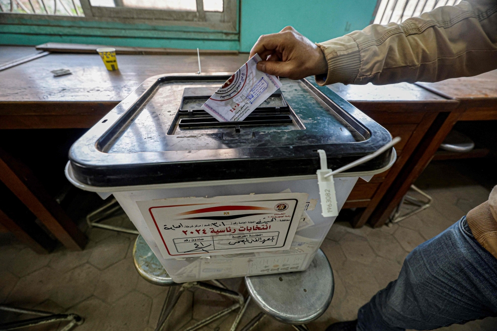 An Egyptian man casts his ballot at a polling station in Imbaba district during the presidential election in Cairo on December 11, 2023.(Photo by Khaled DESOUKI / AFP)