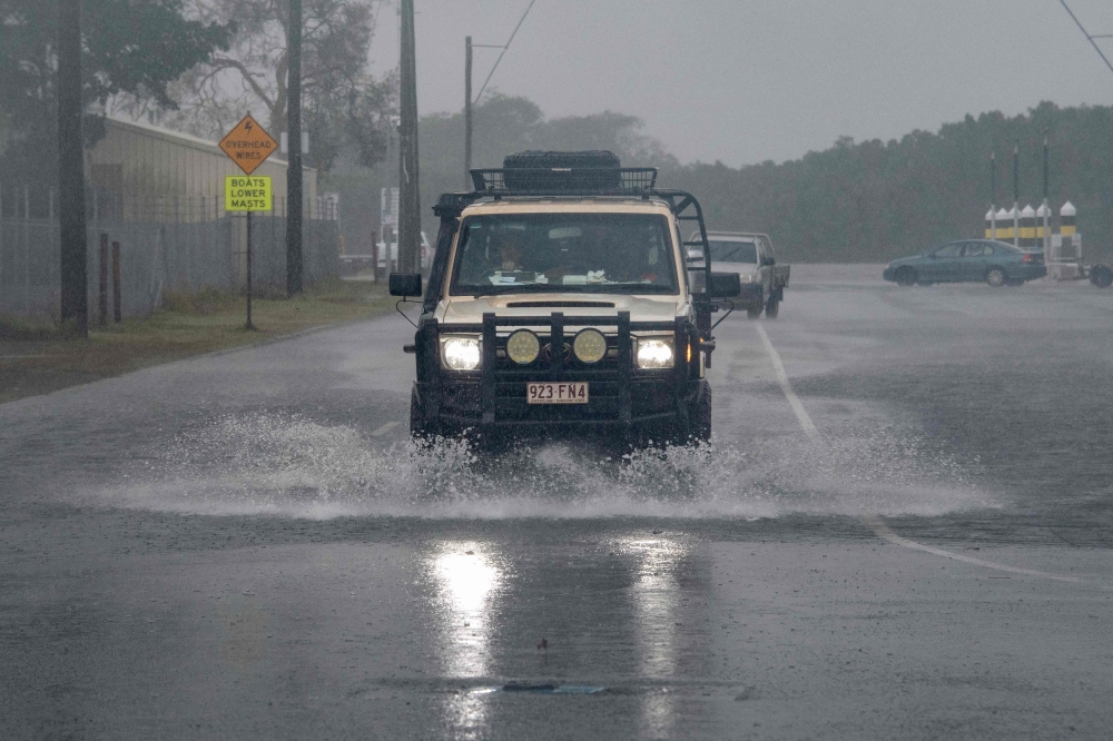 A motorist drives through floodwater as Cyclone Jasper approaches landfall in Cairns in far north Queensland on December 13, 2023. Photo by Brian CASSEY / AFP