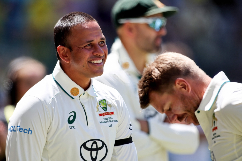 Australia's David Warner (R) and teammate Usman Khawaja leave at the lunch break during the first day of the first Test cricket match against Pakistan on December 14, 2023. (Photo by Colin Murty / AFP) 