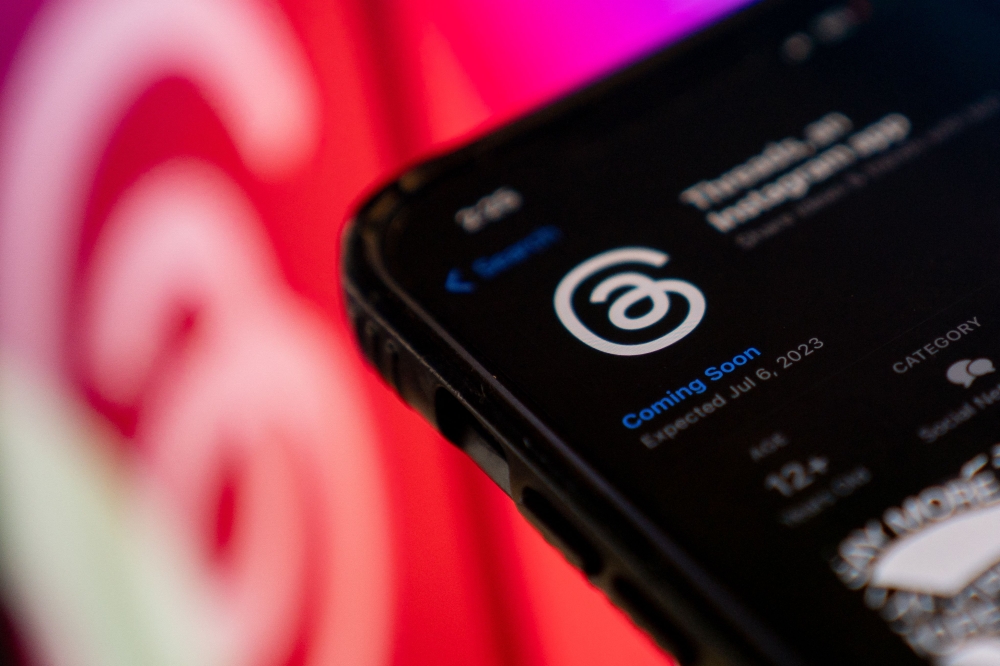 This photo illustration created in Washington, DC, on July 5, 2023, shows Threads, an Instagram app, on the App Store, in front of the logos of Instagram and Threads. Photo by Stefani Reynolds / AFP