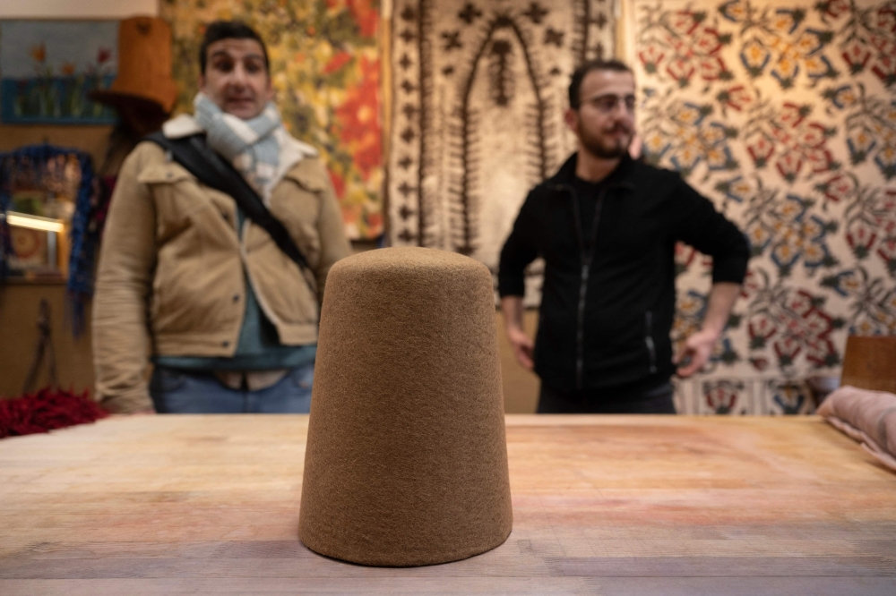 Yunus Girgic (R) and his customer Ashmi Benmehidi (L), a French musician stand in front of a traditional hat 