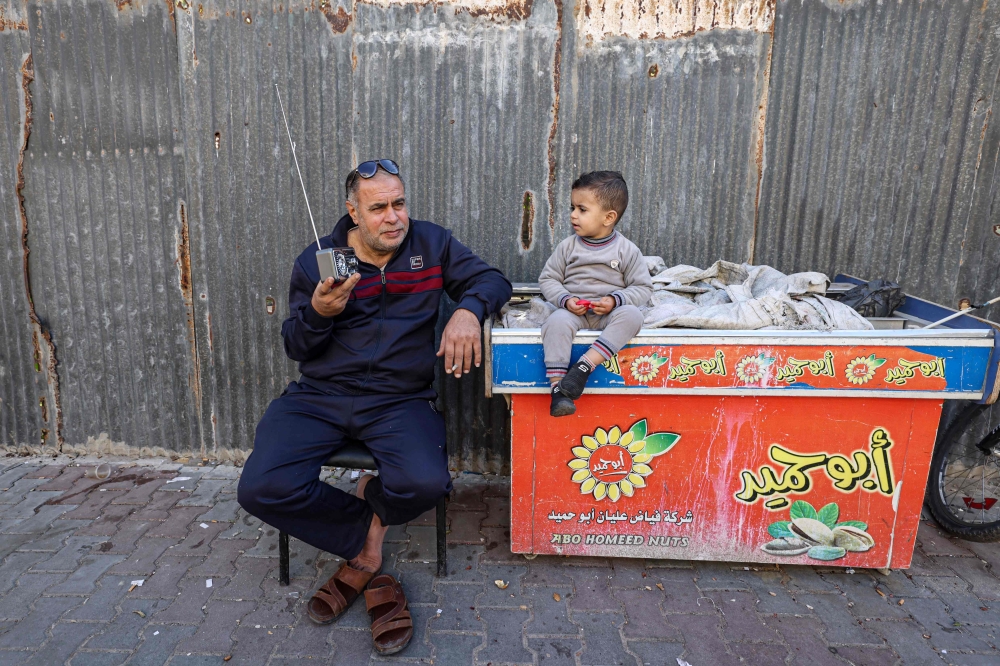 A Palestinian man listens to his radio in a refugee camp in Rafah in the southern Gaza Strip on December 19, 2023. (Photo by Mohammed Abed / AFP)
 
