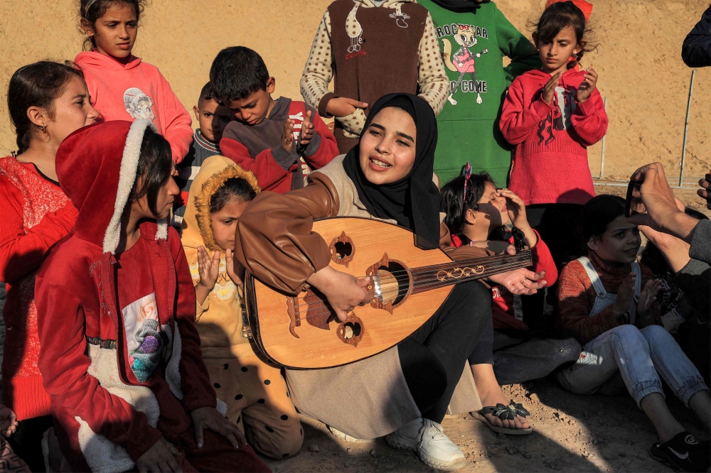 Ruaa Hassouna plays music for Palestinian children on her Oud (Ud, or oriental lute) as Palestinian children participate in an activity aimed to support their mental health on December 18, 2023. (Photo by Said Khatib / AFP)