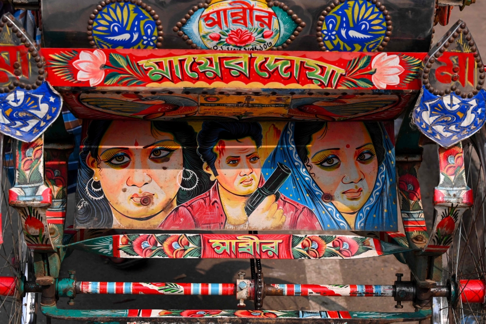 This photograph taken on December 13, 2023 shows a bicycle rickshaw adorned with colourful artwork depicting film actors, in Dhaka. (Photo by Munir Uz Zaman / AFP)