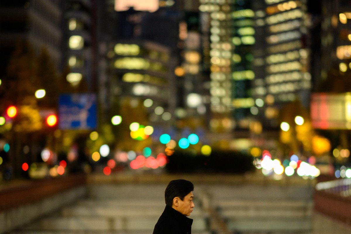 A pedestrian walks in Tokyo's Ginza district at dusk on December 13, 2023. (Photo by Philip FONG / AFP)
