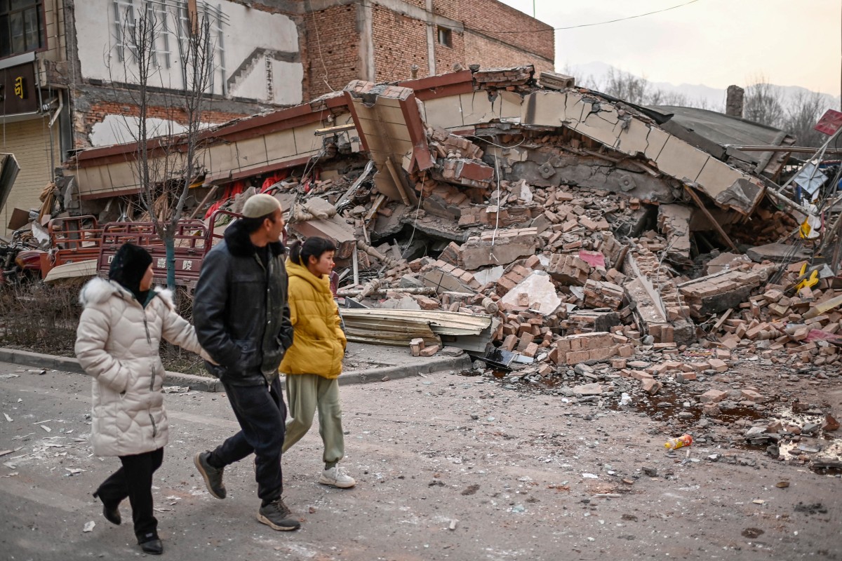 People walk past a collapsed building after an earthquake in Dahejia, Jishishan County in northwest China’s Gansu province on December 19, 2023. (Photo by Pedro Pardo / AFP)
