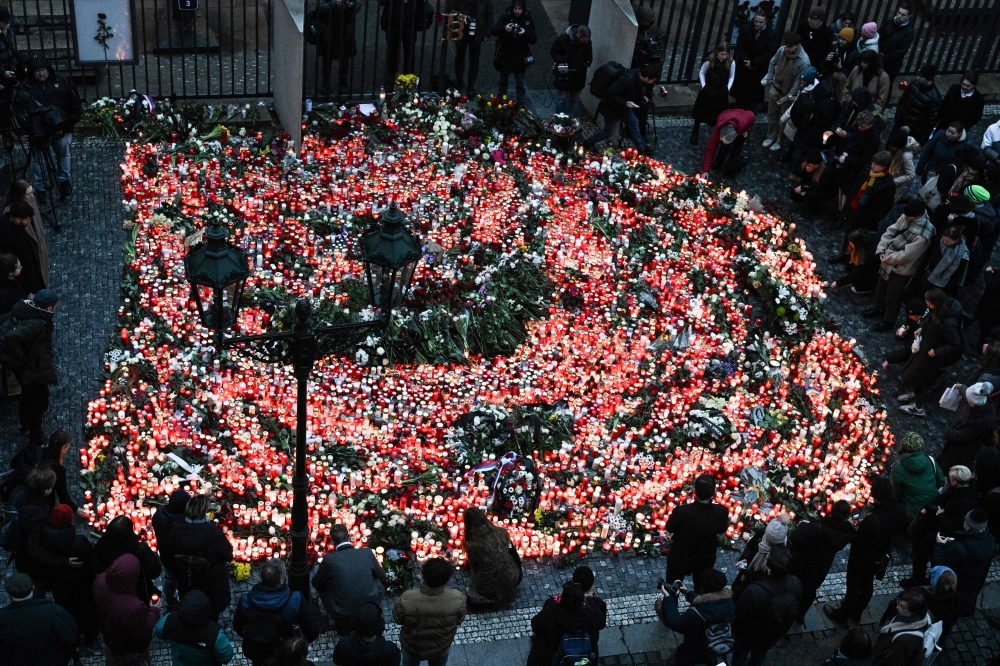 Well wishers light candles as people mourn at a makeshift memorial for the victims outside the Charles University in central Prague, on December 22, 2023, as police investigators kept working on the campus the day after a deadly mass shooting. (Photo by Michal Cizek / AFP)
