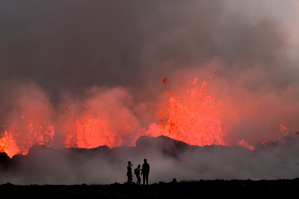 People watch flowing lava during an volcanic eruption near Litli Hrutur, south-west of Reykjavik in Iceland on July 10, 2023. (Photo by Kristinn Magnusson / AFP)