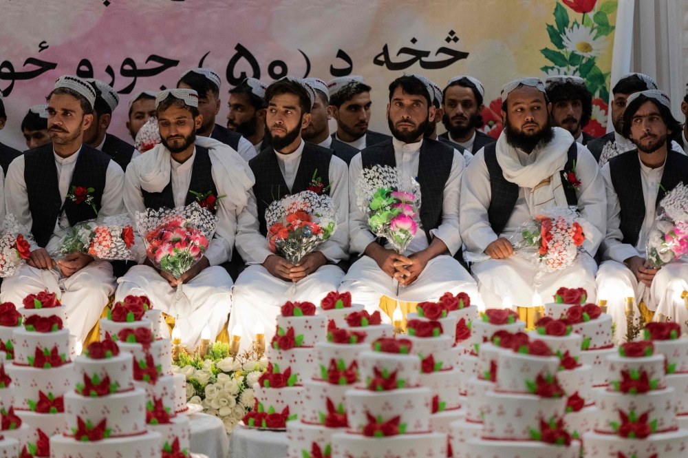 Afghan grooms look on during a mass wedding ceremony at a wedding hall in Kabul on December 25, 2023. (Photo by Wakil KOHSAR / AFP)
