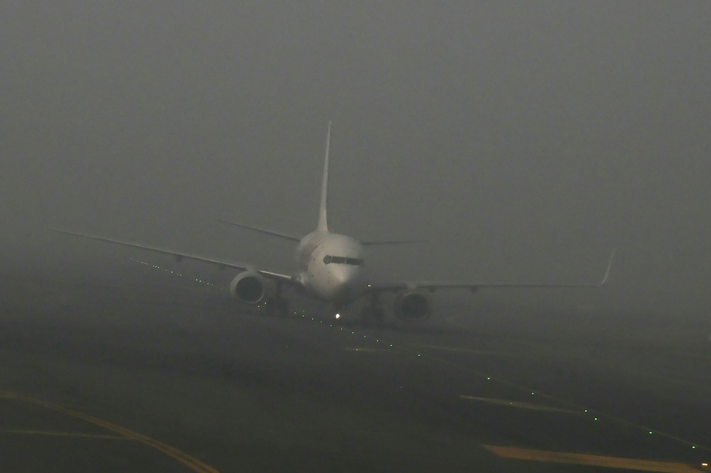 An aircraft prepares to take off amid dense fog on a cold winter morning at Indira Gandhi International Airport in New Delhi on December 27, 2023. (Photo by Arun SANKAR / AFP)