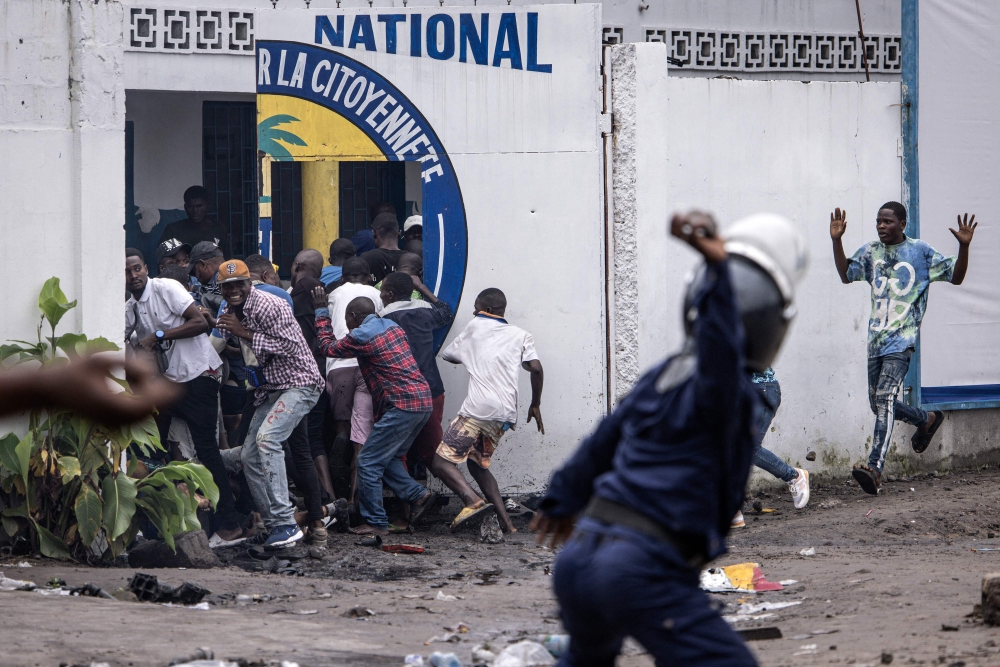 A Police officer throws a rock as opposition supporters run into a opposition leader Martin Fayulu's party house during a demonstration in Kinshasa on December 27, 2023. (Photo by JOHN WESSELS / AFP)
