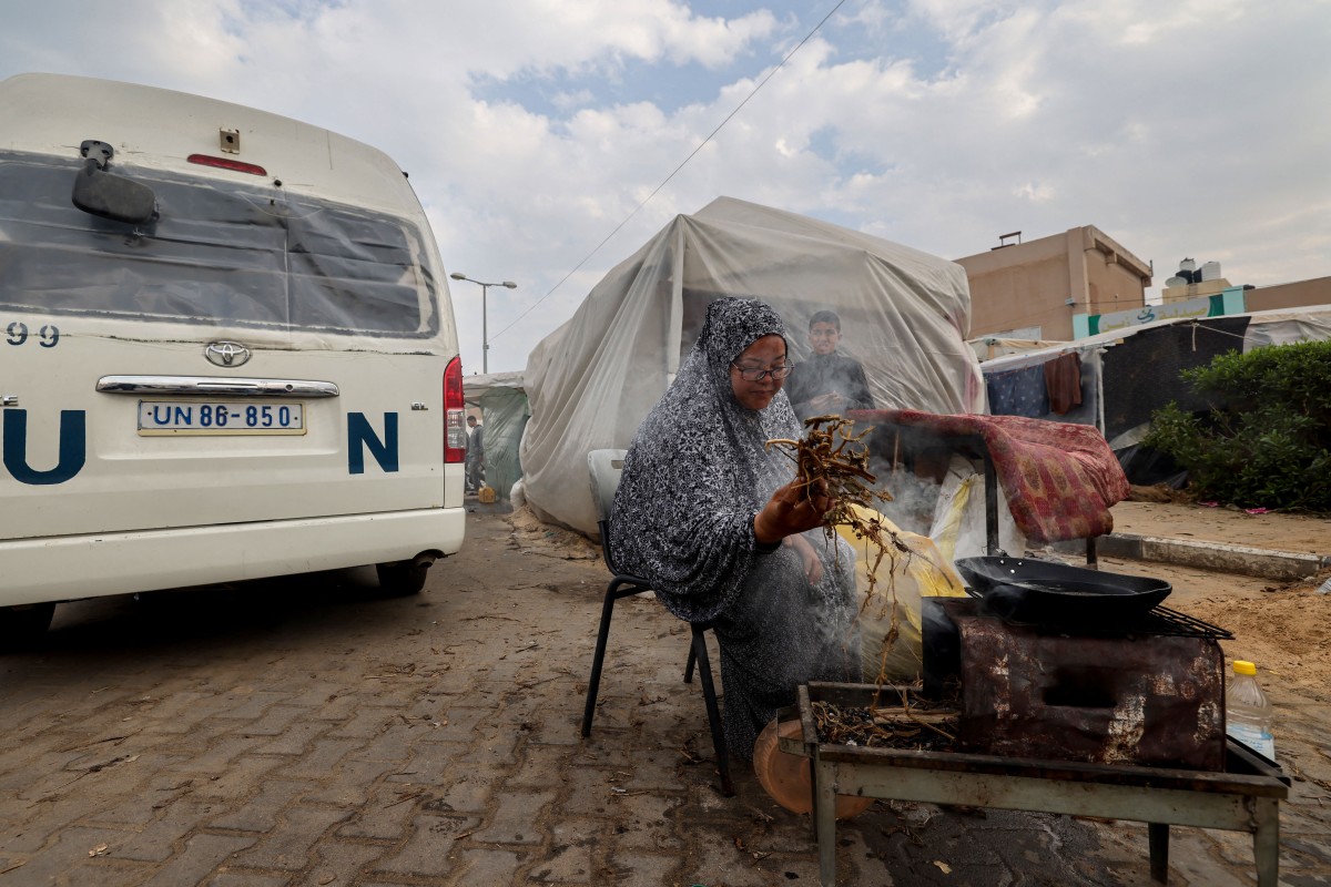 A displaced Palestinian woman lights a cooking fire outside a tent in Rafah in the southern Gaza Strip on December 27, 2023. (Photo by Mohammed Abed / AFP)

