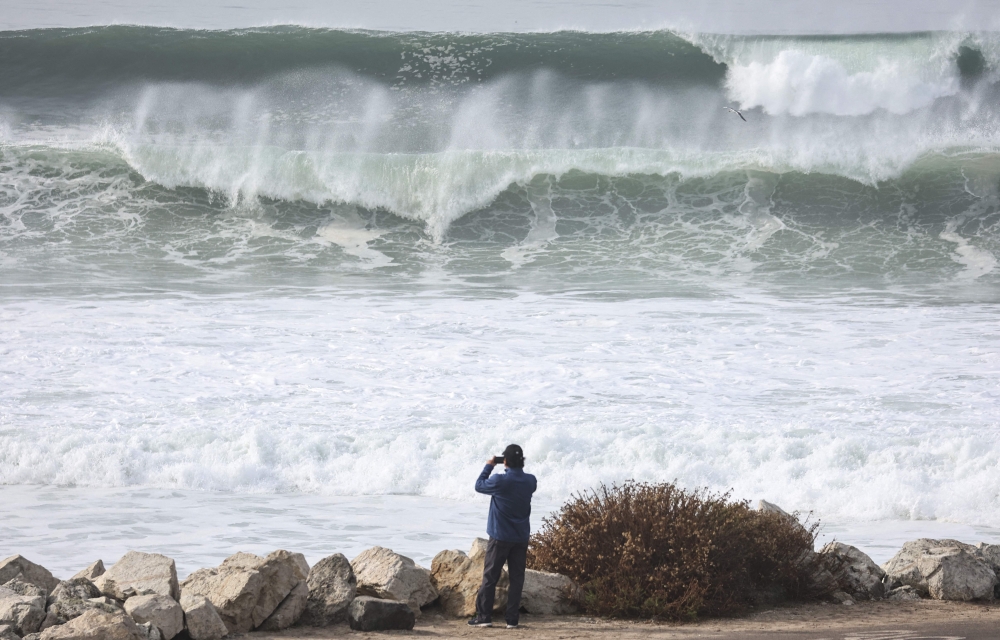 A person takes photos as large waves break near the beach on December 29, 2023 in Manhattan Beach, California. Mario Tama/Getty Images/AFP 
