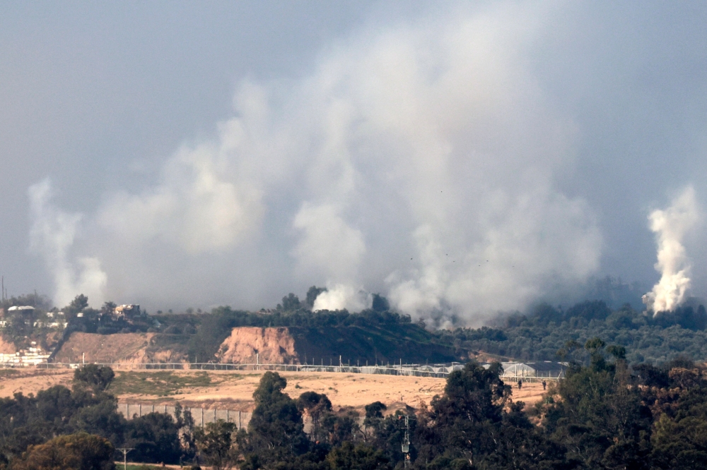 Plumes of smoke rising over Gaza City during Israeli strikes on December 31, 2023. (Photo by Menahem Kahana / AFP)