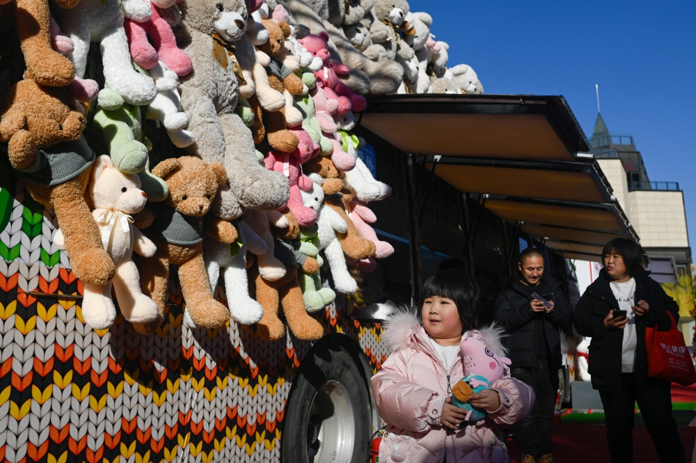 A child walks past a toy shop converted from a trailer along a business street in Beijing on January 3, 2024. (Photo by WANG Zhao / AFP)