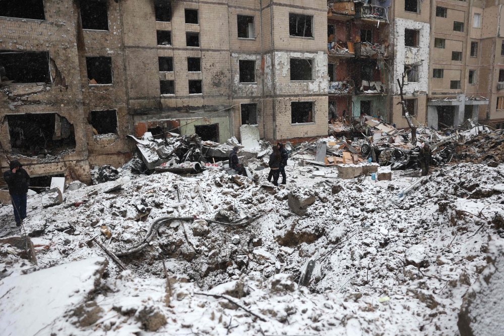 Police officers and local residents inspect damage outside a destroyed high-rise building following a Russian missile attack in central Kyiv, on January 3, 2024, amid the Russian invasion of Ukraine. (Photo by Anatolii STEPANOV / AFP)
