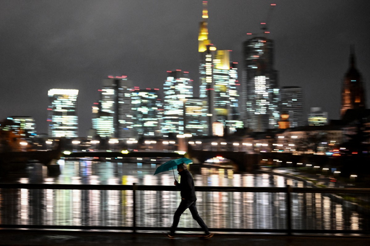 A man with an umbrella crosses the Main river on a rainy day in Frankfurt am Main, western Germany, on January 2, 2024. (Photo by Kirill KUDRYAVTSEV / AFP)

