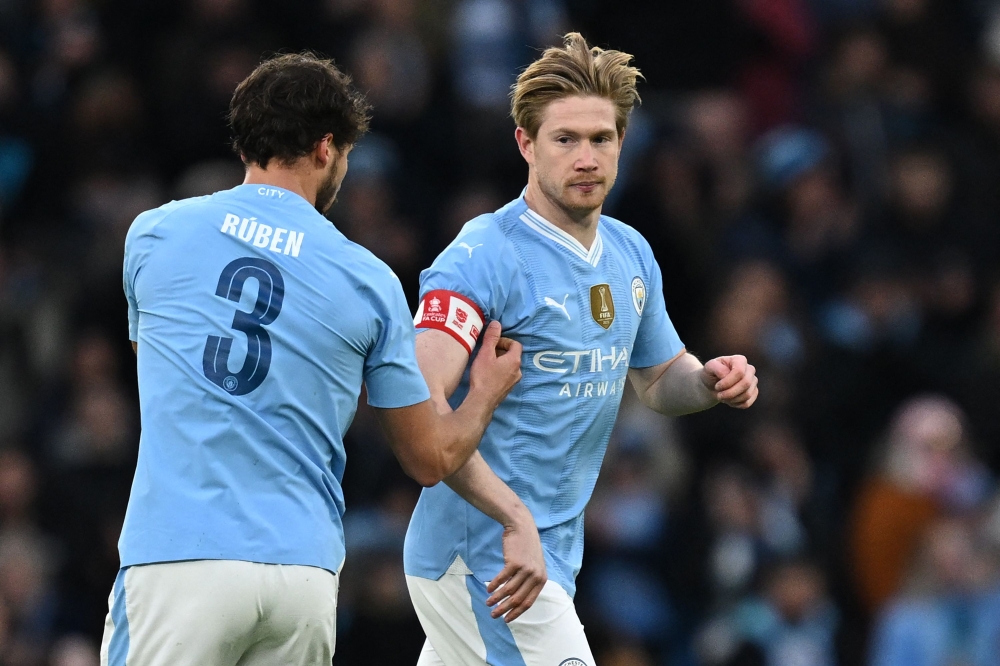 Manchester City's Portuguese defender #03 Ruben Dias (L) passes the captain's armband to Manchester City's Belgian midfielder #17 Kevin De Bruyne (R) during the English FA Cup third round football match between Manchester City and Huddersfield Town at the Etihad Stadium in Manchester, north west England, on January 7, 2024. Photo by Paul ELLIS / AFP