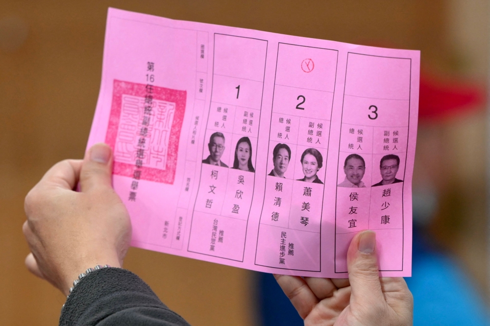An official of a polling station examines a ballot slip, as vote counting for the presidential election commences, at a high school in New Taipei City on January 13, 2024. (Photo by Sam Yeh / AFP)