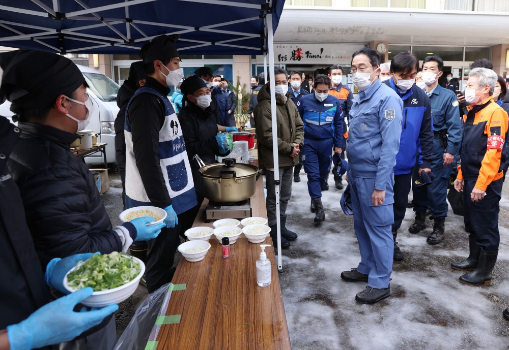 Japan's Prime Minister Fumio Kishida (C) speaks to a group who are running a soup kitchen at an evacuation center in Suzu city of Ishikawa Prefecture on January 14, 2024, after a major 7.5 magnitude earthquake struck the Noto region in Ishikawa prefecture on New Year's Day. Photo by JAPAN POOL / JIJI PRESS / AFP