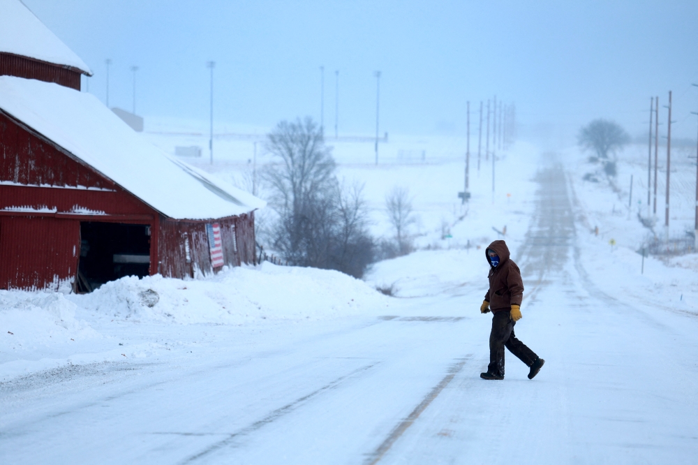 A person walks back to his home after checking the mailbo as a snowy and freezing cold weather system passes through the area on January 13, 2024, in Casey, Iowa.  (Photo by JOE RAEDLE / GETTY IMAGES NORTH AMERICA / Getty Images via AFP)

