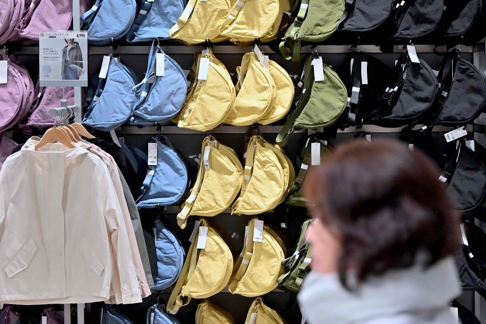 A woman walks past a display of bags at a Uniqlo retail store in Tokyo on January 16, 2024. Photo by Richard A. BROOKS / AFP