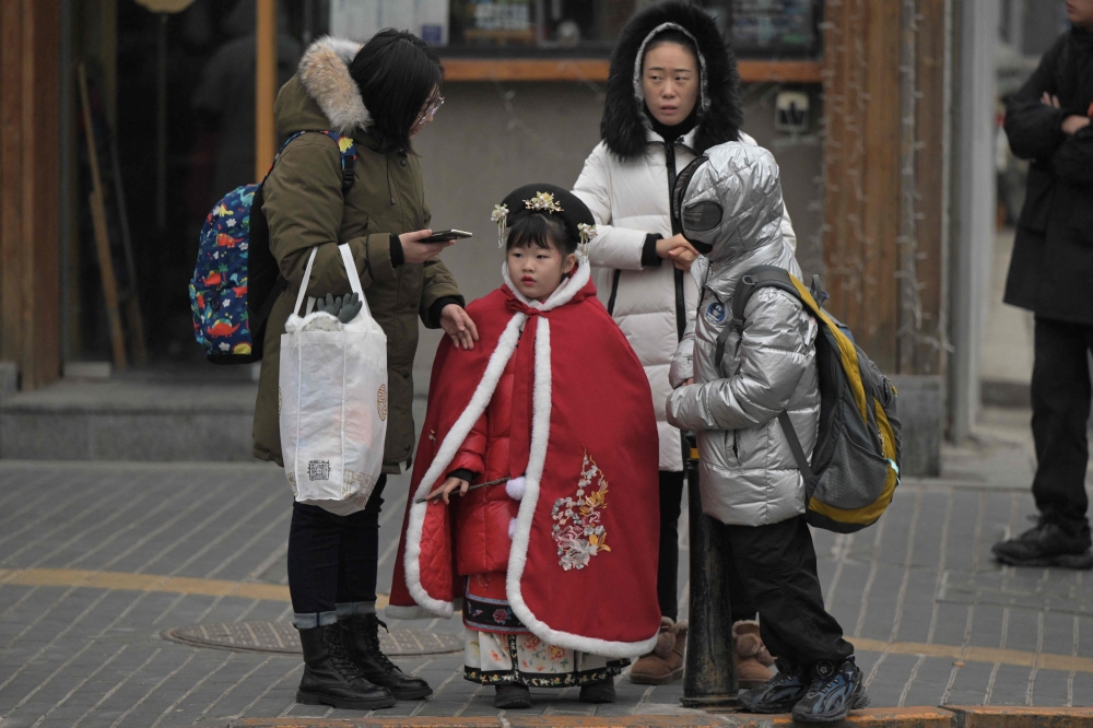 People are seen on a street in Beijing on January 17, 2024. (Photo by Pedro Pardo / AFP) 