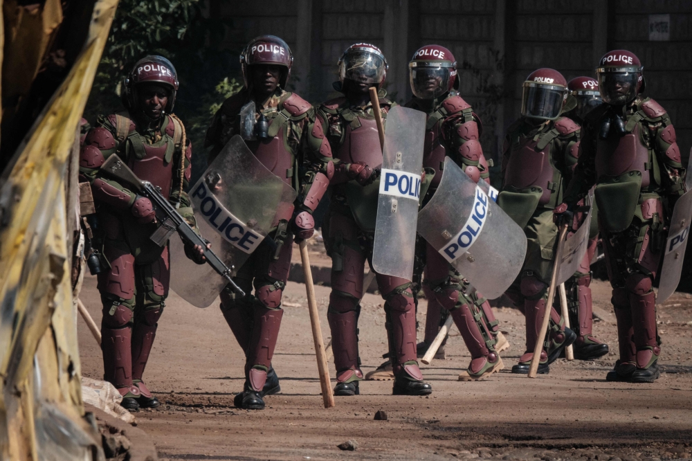 (FILES) Kenyan Police officers watch protesters as they block the street during a mass rally called by the opposition leader Raila Odinga who claims the last Kenyan presidential election was stolen from him and blames the government for the hike of living costs in Kibera, Nairobi on March 27, 2023. (Photo by YASUYOSHI CHIBA / AFP)
