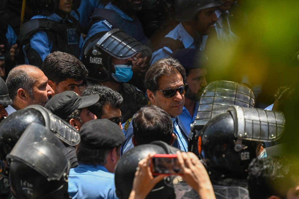 Policemen escort Pakistan's former Prime Minister Imran Khan (C) upon his arrival at the high court in Islamabad on May 12, 2023. (Photo by Aamir Qureshi / AFP)