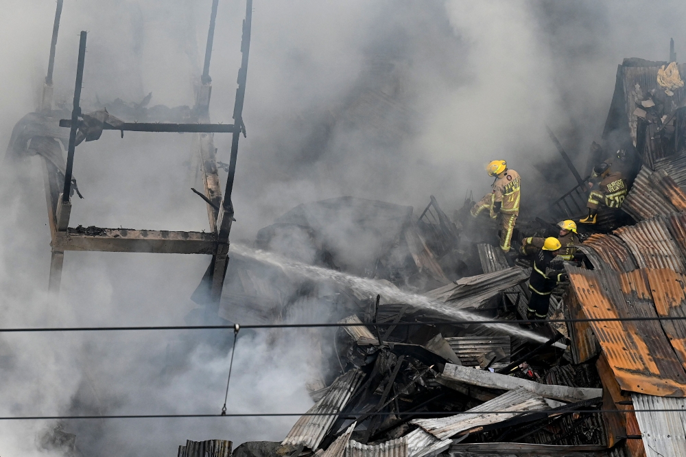 Firefighters respond as a huge fire engulfs buildings at a crowded neighborhood in Manila on January 31, 2024. (Photo by JAM STA ROSA / AFP)