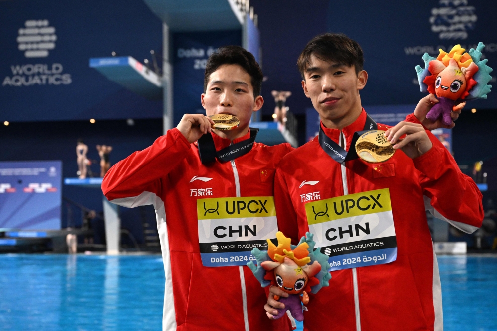 Gold medallists China's Wang Zongyuan and Long Daoyi pose during the medal ceremony of the final of the men's 3m springboard synchro diving event during the 2024 World Aquatics Championships at Hamad Aquatics Centre in Doha on February 4, 2024. (Photo by Oli SCARFF / AFP)
