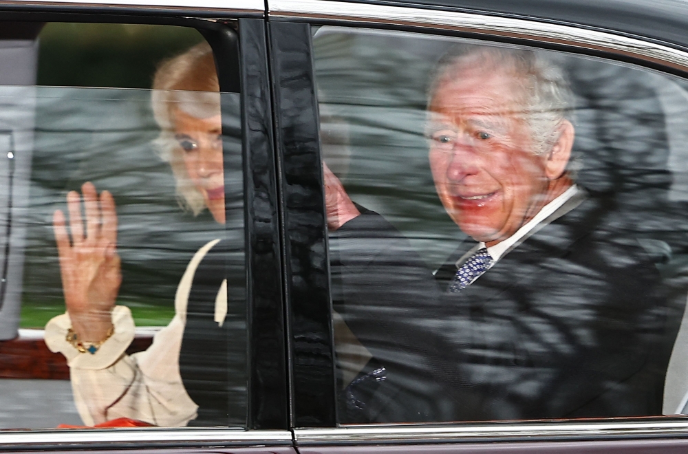 Britain's King Charles III and Britain's Queen Camilla wave as they leave by car from Clarence House in London on February 6, 2024. (Photo by Henry Nicholls / AFP)

