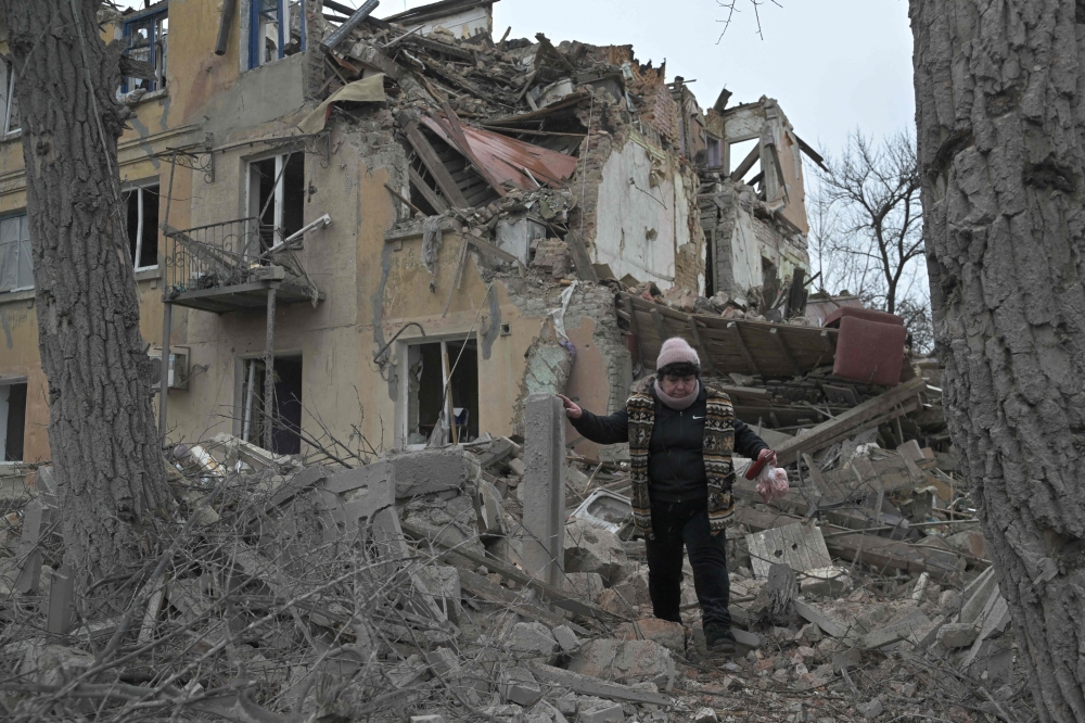 A woman walks among debris of a residential building partially destroyed by a missile attack in the town of Selydove, Donetsk region, on February 8, 2024, amid the Russian invasion of Ukraine. (Photo by Genya Savilov / AFP)