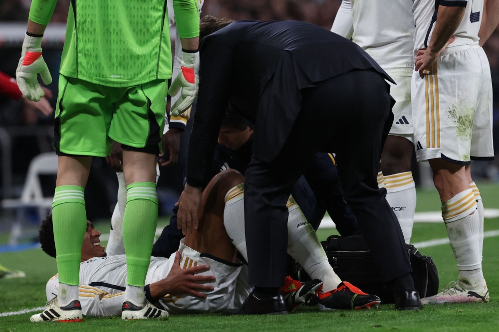 Real Madrid's English midfielder #5 Jude Bellingham (down) receives medical treatment during the Spanish league football match between Real Madrid CF and Girona FC at the Santiago Bernabeu stadium in Madrid on February 10, 2024. (Photo by Pierre-Philippe Marcou / AFP)