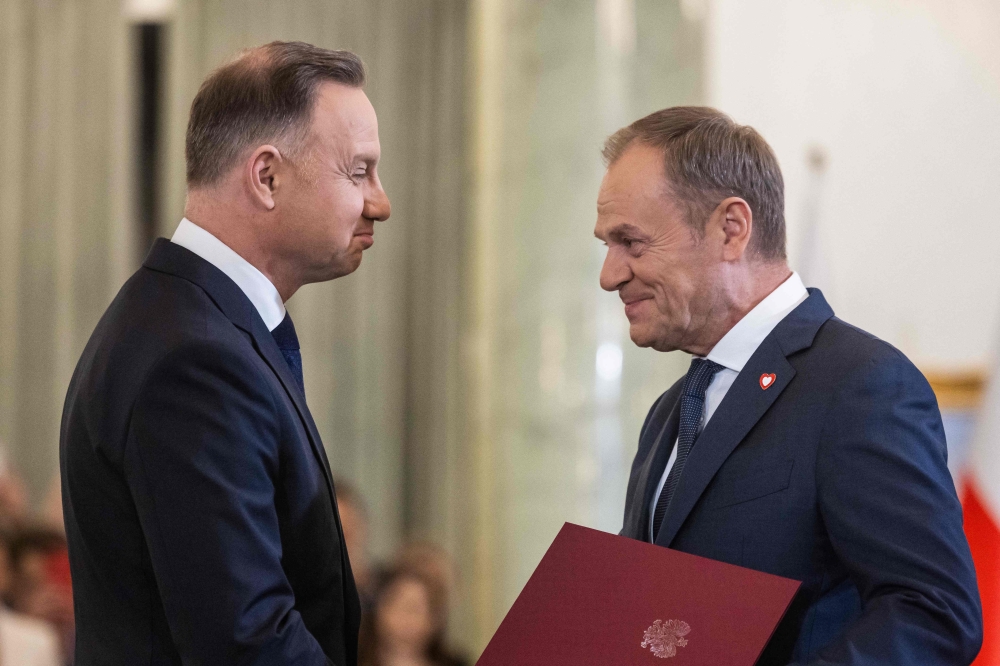 Poland's President Andrzej Duda (left) hands the assignment document to Donald Tusk to designate him as Poland's Prime Minister, during a formal swearing-in ceremony at the Presidential Palace in Warsaw, Poland, on December 13, 2023. (Photo by Wojtek Radwanski / AFP)