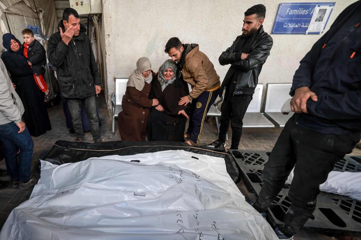 Palestinians mourn near the bodies of loved ones following Israeli bombardment on Rafah in the southern Gaza Strip, at al-Najar hospital on February 16, 2024 (Photo by MOHAMMED ABED / AFP)