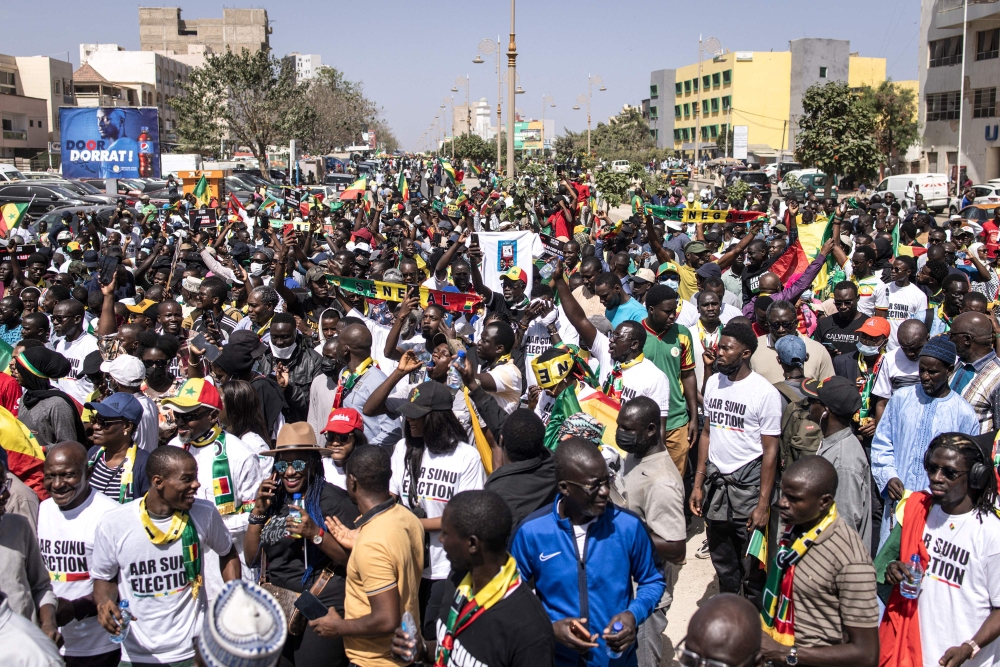 Civil society groups and political groups hold placards as they march calling on authorities respect the election date, in Dakar, on February 17, 2024. (Photo by JOHN WESSELS / AFP)
